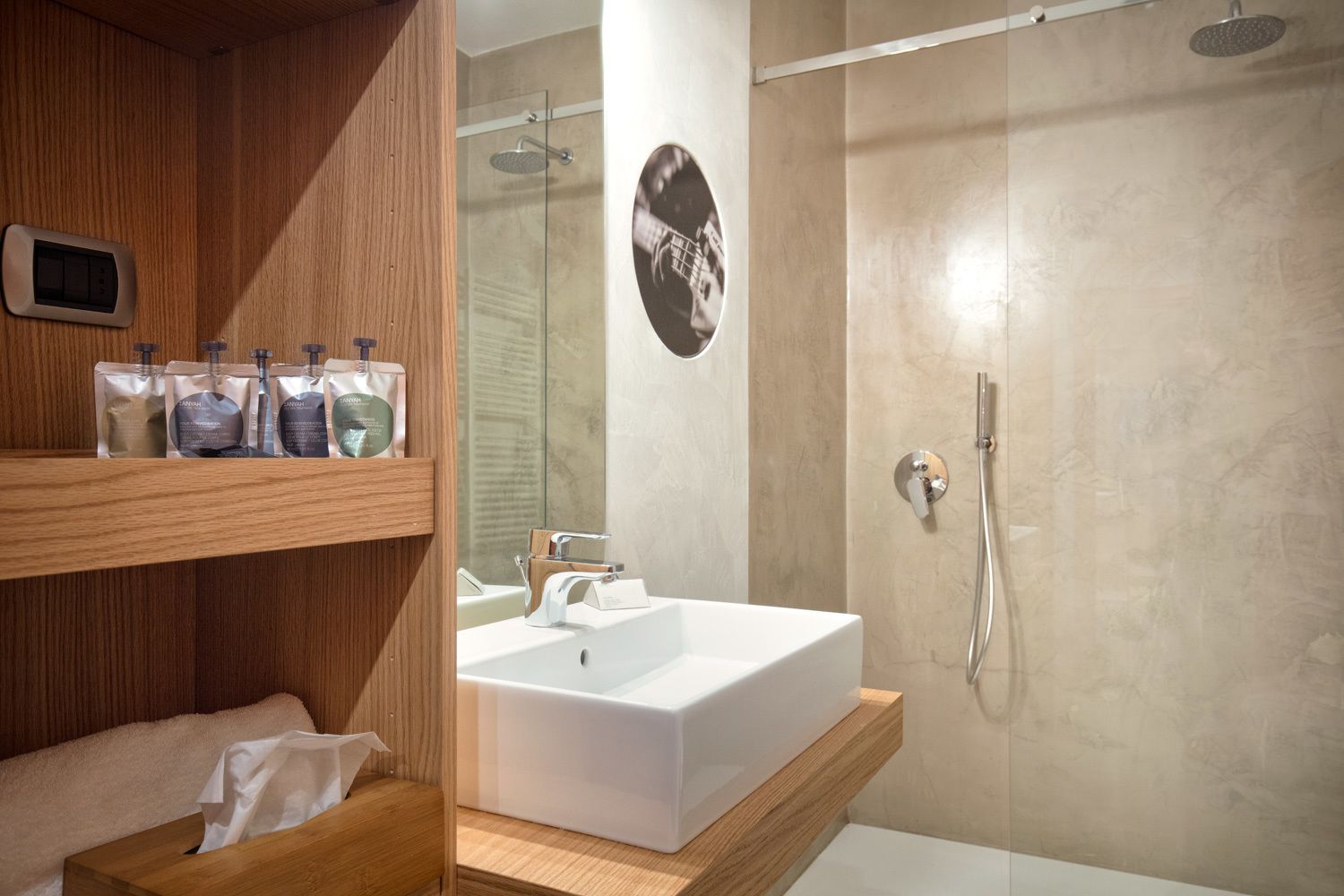 A modern bathroom with a wooden vanity, a white sink, and a glass shower enclosure.