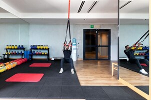 Une salle de sport équipée de matériel d’exercice, notamment des kettlebells et des systèmes d’entraînement en suspension TRX.