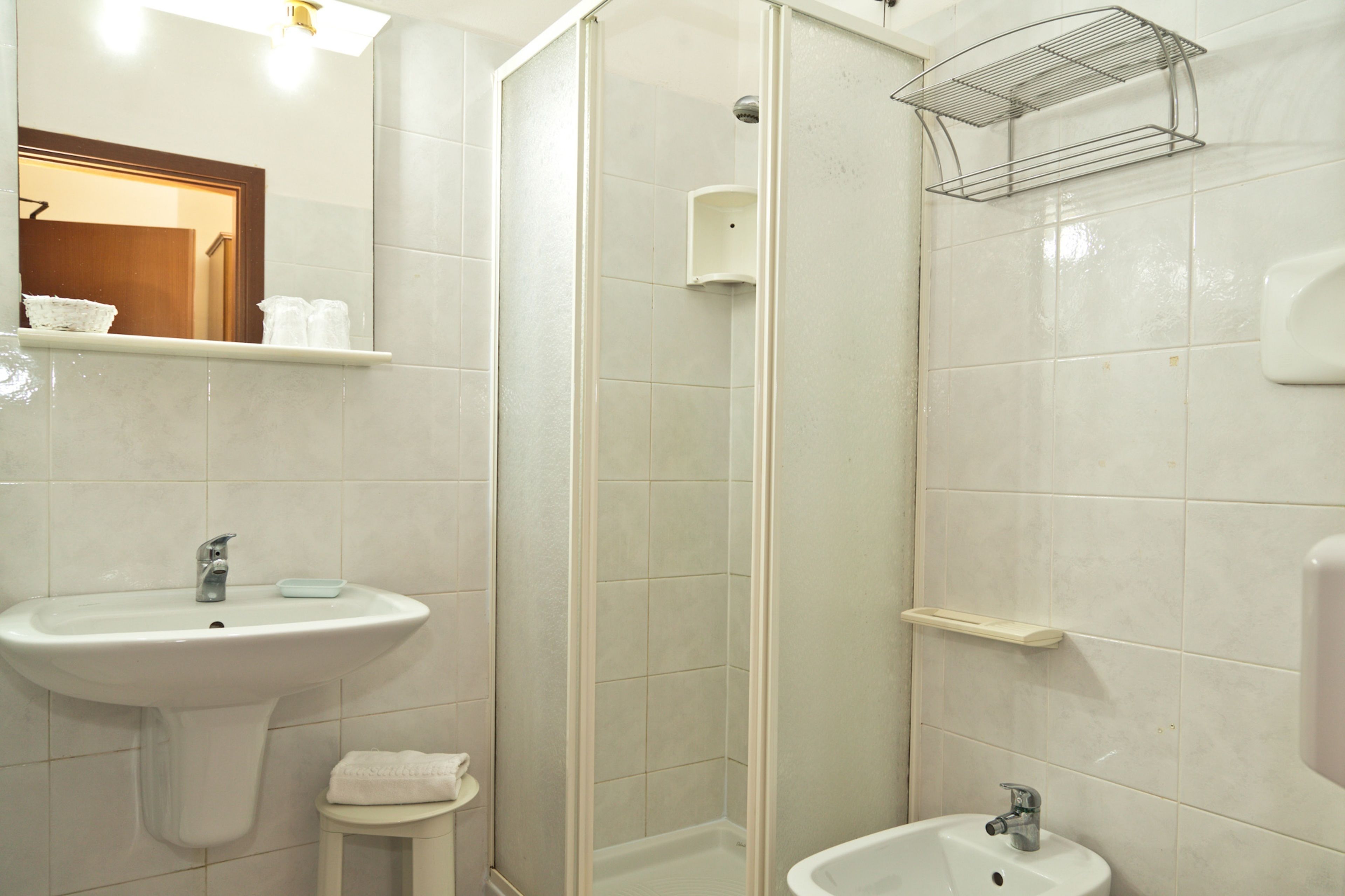 Ein Badezimmer mit Waschbecken, Spiegel, Handtuchhalter, Dusche und Toilette.