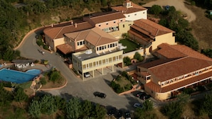An aerial view of a large, multi-story residential building with a swimming pool, multiple garages, and a well-maintained lawn. - Pausania Inn (Tempio Pausania)