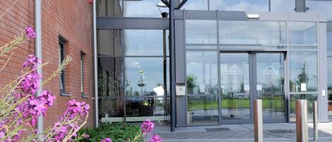 Una entrada moderna a un edificio con puertas de vidrio y un vestíbulo cubierto.