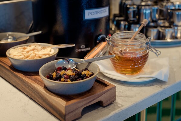 A kitchen counter with a wooden tray holding two bowls of food, a jar of honey, and a bottle of porridge.
