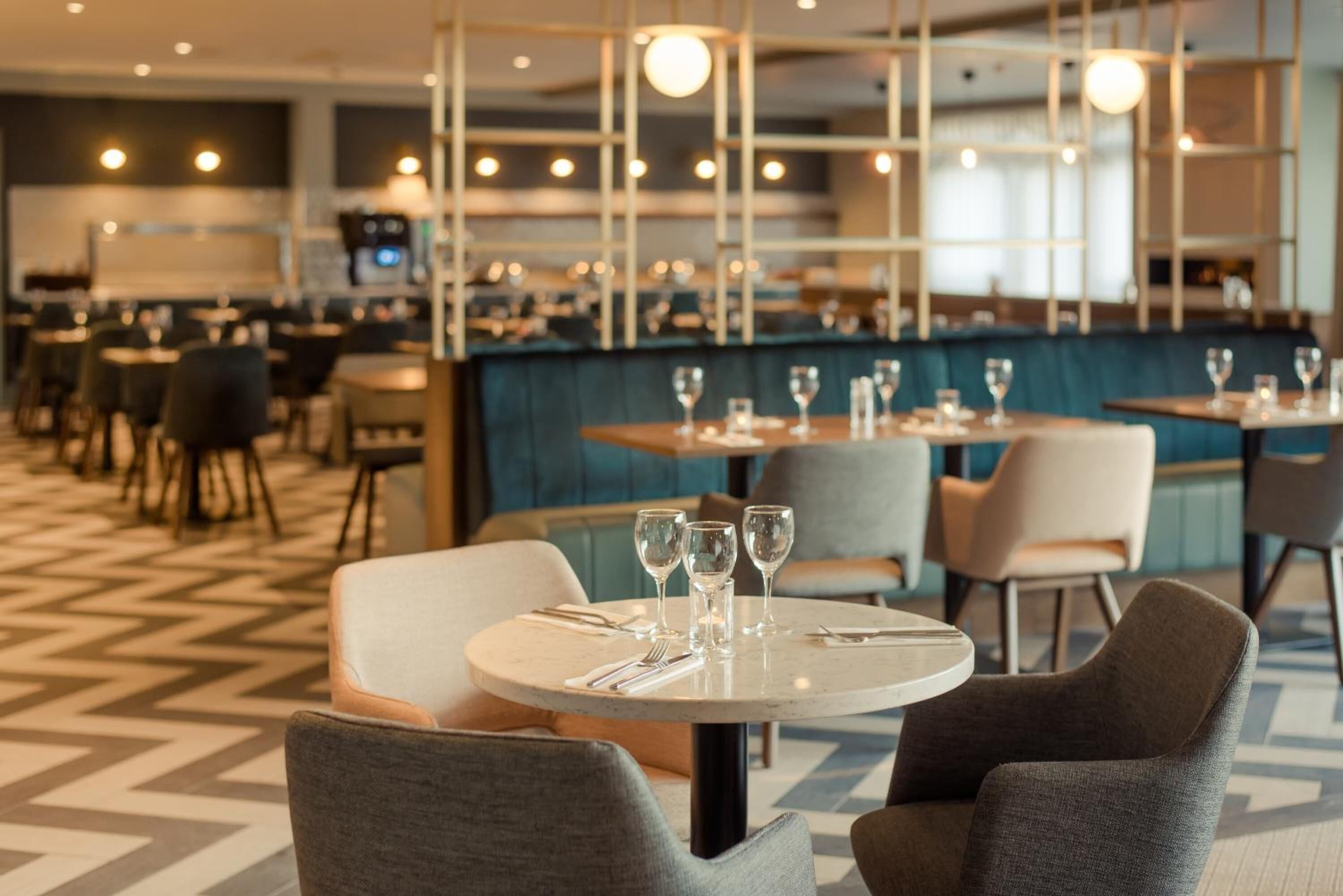 Un restaurant avec des tables rondes, des chaises et un coin bar.