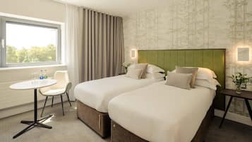 Habitació d'hotel amb dos llits, una taula petita i una cadira.