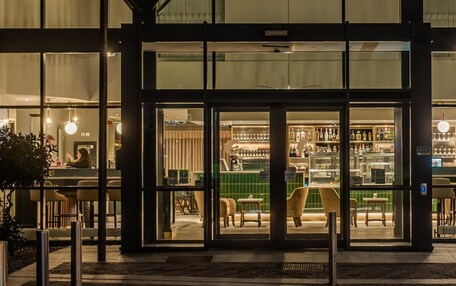 Un edificio moderno con entrada de vidrio, asientos interiores y una zona de bar.