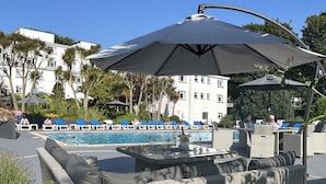 Een zwembadgedeelte met ligbedden, een grote parasol en een zwembad.