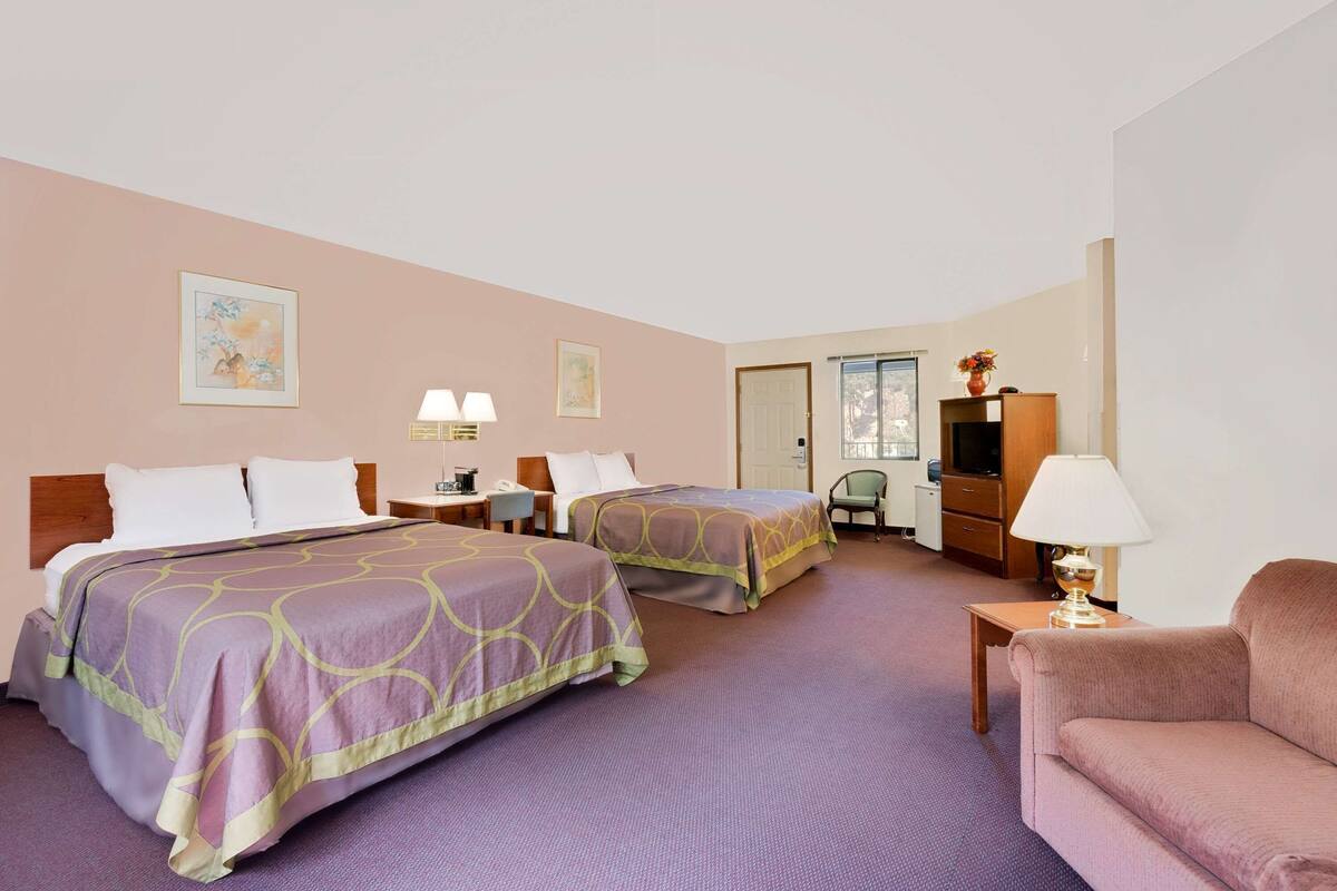 Habitación de hotel con dos camas, un sofá, un televisor, un escritorio y una silla.