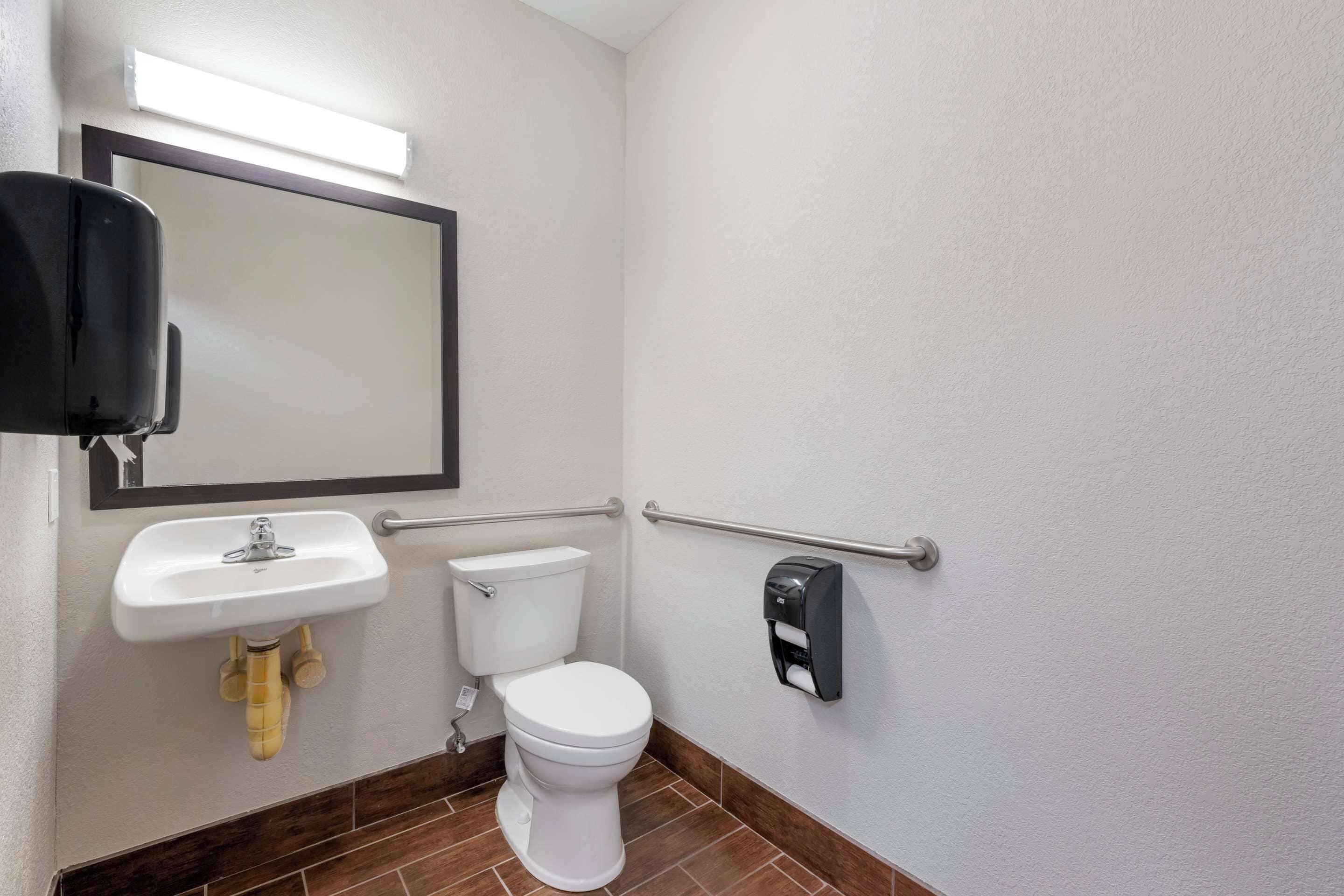 Un baño pequeño con un lavabo, inodoro y secamanos blancos.