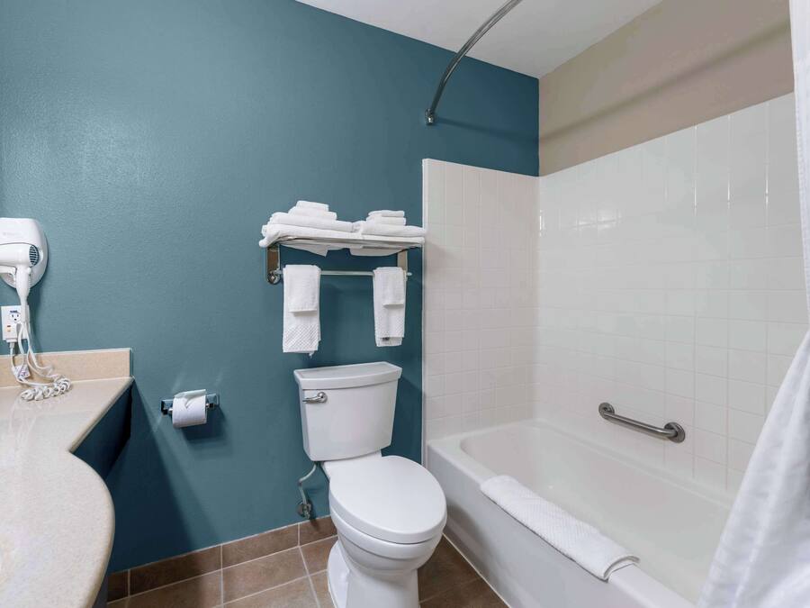 A bathroom with a toilet, a sink, a hairdryer, a towel rack, and a bathtub.