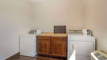 A laundry room with two washing machines, a dryer, and a wooden cabinet.