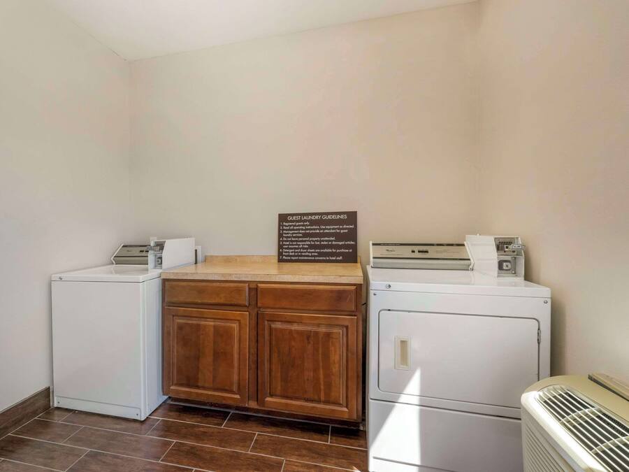 A laundry room with two washing machines, a dryer, and a wooden cabinet.