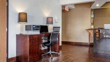 A reception desk with a computer, a chair, and a lamp.