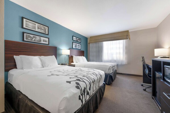 A hotel room with two beds, a desk, a chair, and a TV. - Sleep Inn & Suites Hays I-70 (Hays)