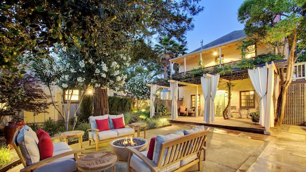 An outdoor patio with seating, a fire pit, and a covered area with a view of the house.