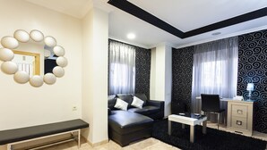 A modern living room with a black leather sofa, a round mirror, a desk, and a black rug. - Hotel Manolo (Cartagena)