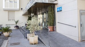 A hotel entrance with a metal railing, potted plants, and a blue parking sign. - Hotel Manolo (Cartagena)
