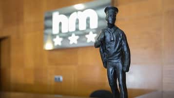 Una statua di un uomo in divisa, con un cartello illuminato sullo sfondo.