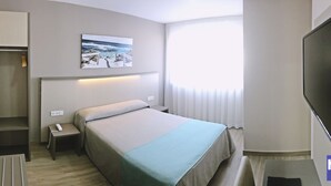 A hotel room with a bed, bedside table, lamp, and a television. - Hotel Manolo (Cartagena)