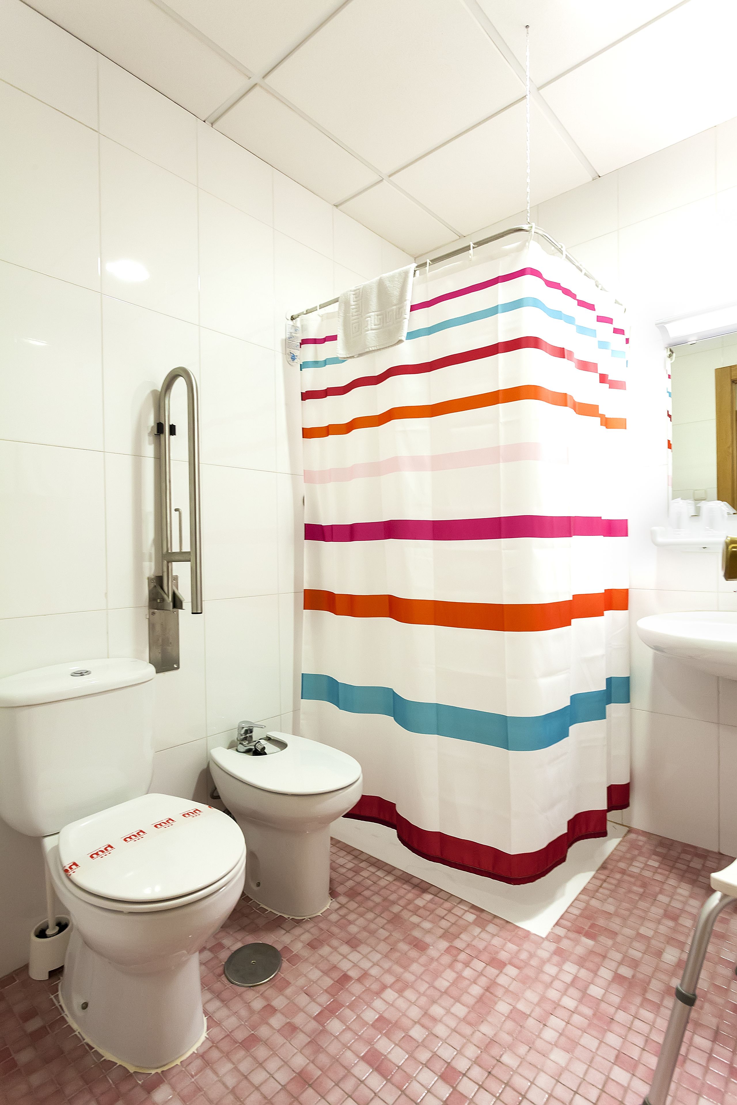Een badkamer met twee toiletten, een douchegordijn en een wastafel.