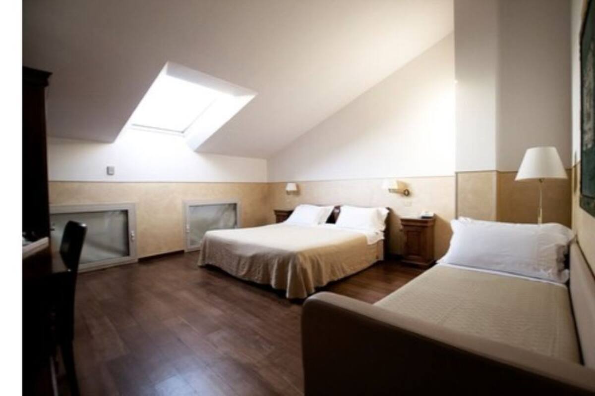 A bedroom with a skylight, a bed, a nightstand, and a lamp.