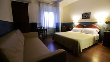 Una camera d'albergo con un letto, un divano, una scrivania e una sedia.