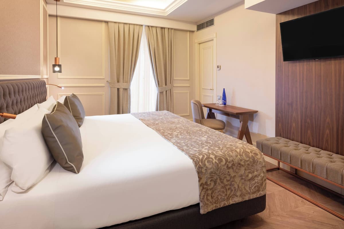 Una habitación de hotel con una cama grande, un escritorio, un televisor y un área de descanso.