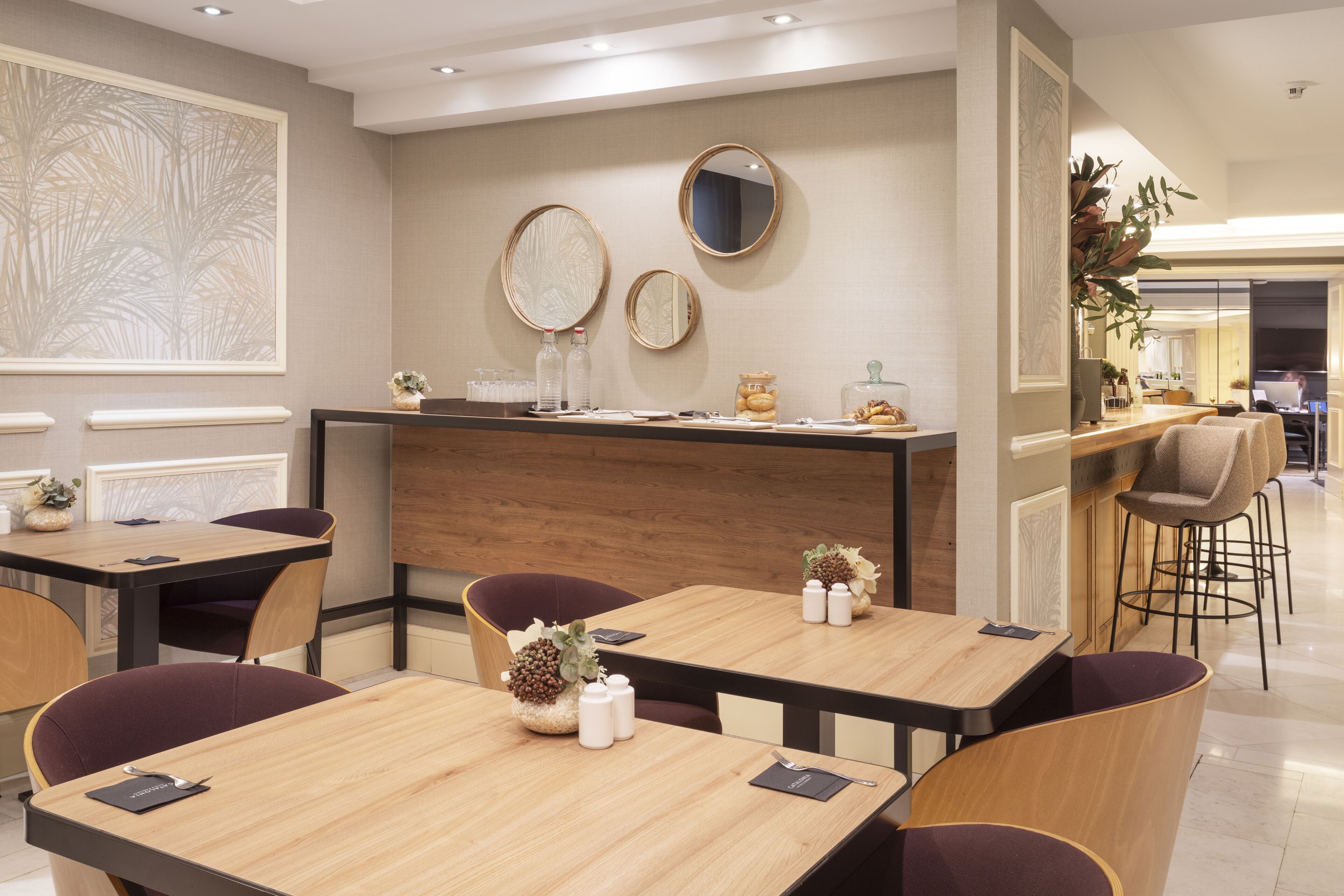 Un comedor moderno con mesas y sillas de madera, una barra y jarrones decorativos.