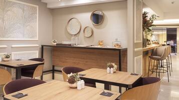 Un comedor moderno con mesas y sillas de madera, una barra y jarrones decorativos.