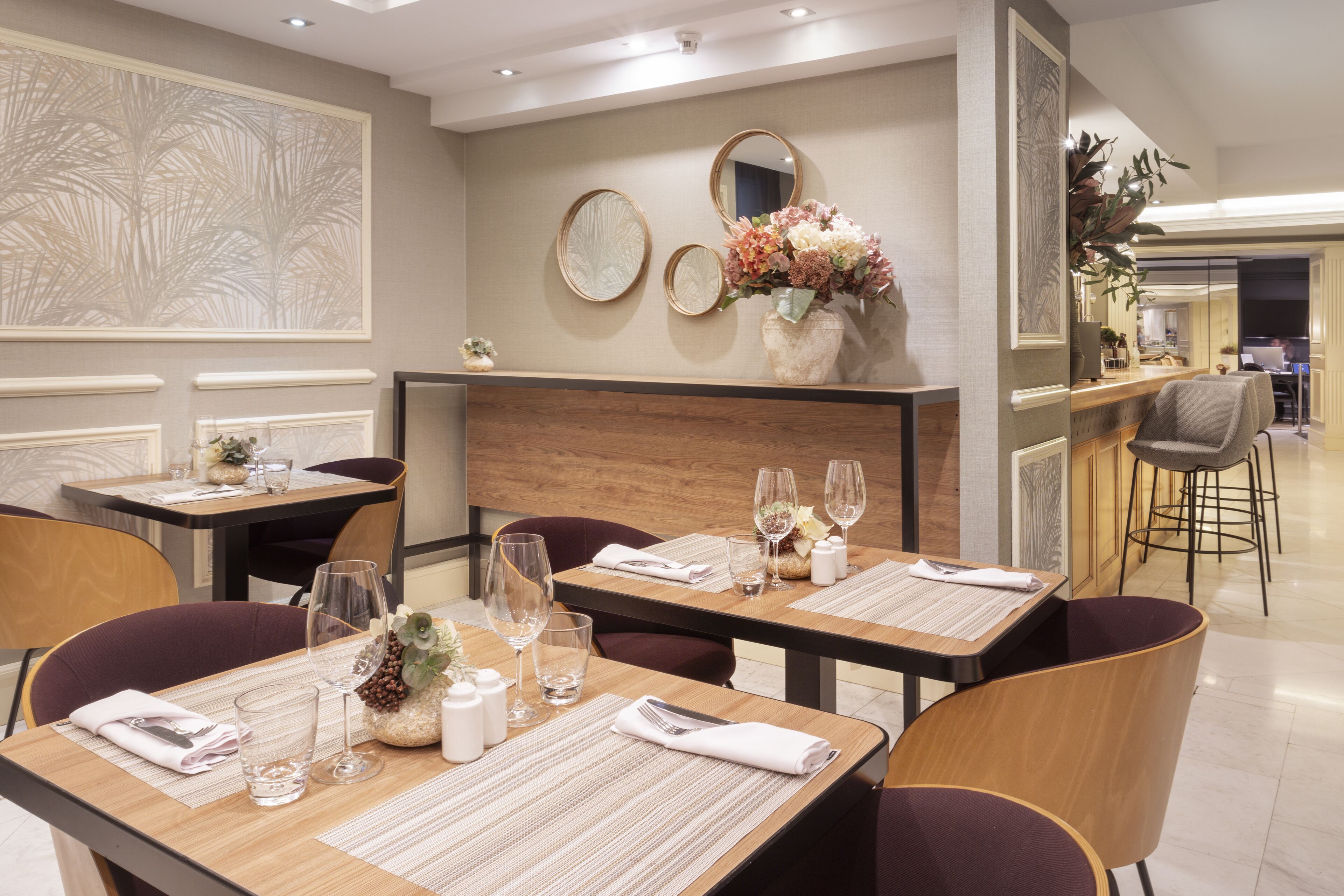 A dining area with tables set for two, featuring placemats, cutlery, and glasses.