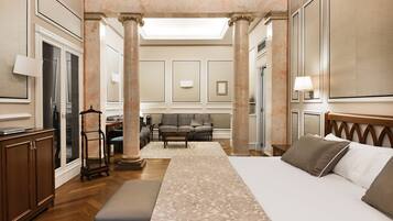 Een ruime hotelkamer met een groot bed, een zithoek met een bank en stoelen, een houten kast en een groot raam.