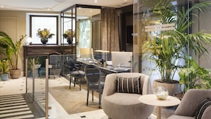 Un hall d’hôtel moderne avec un comptoir d’accueil, un espace salon et des plantes en pot.