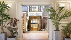 Une entrée imposante avec un plancher en bois menant à un balcon agrémenté de balustrades décoratives et d’une porte ornée.