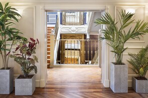 Una entrada imponente con piso de madera que conduce a un balcón con barandilla ornamentada y una puerta decorativa.