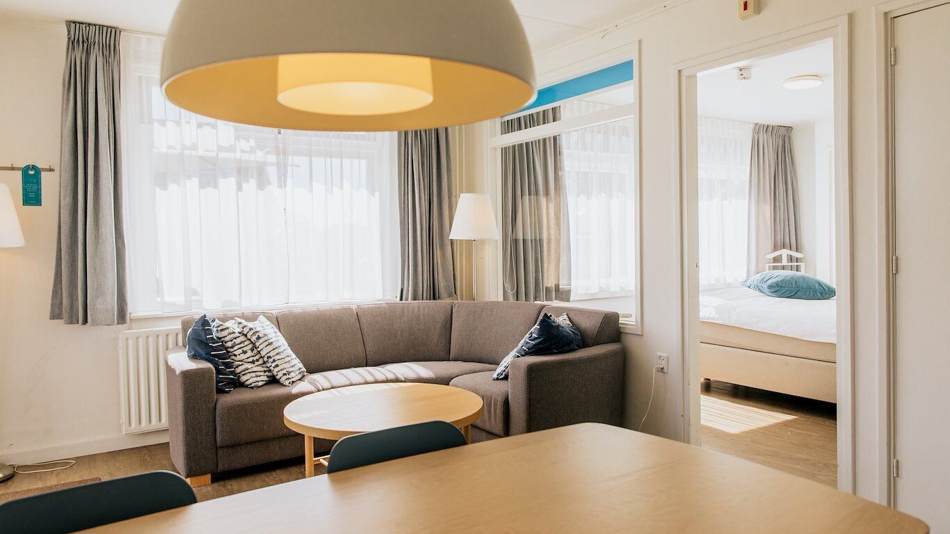 Moderni hotellihuone, jossa on sohva, pyöreä pöytä ja sänky.