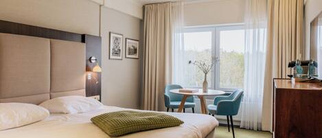 A hotel room with a bed, a desk, a chair, and a window with curtains.