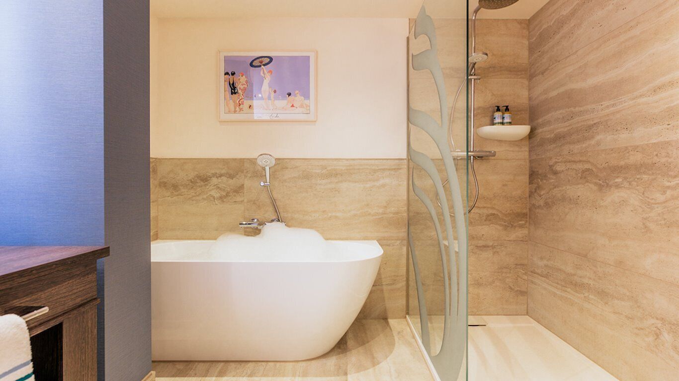 Un baño moderno con una bañera independiente, cabina de ducha con paredes de vidrio y un revestimiento de mármol.