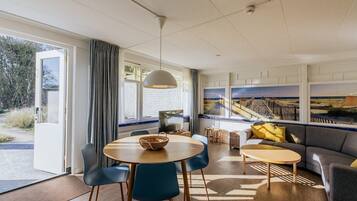 Una sala de estar moderna con un sofá, dos sillones, una mesa de centro y un televisor.