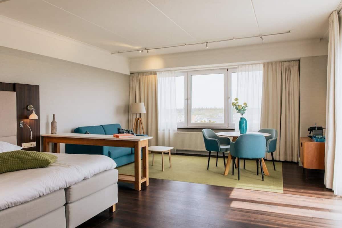 Een hotelkamer met een bed, bureau, stoel, tafel en uitzicht op het omliggende landschap.