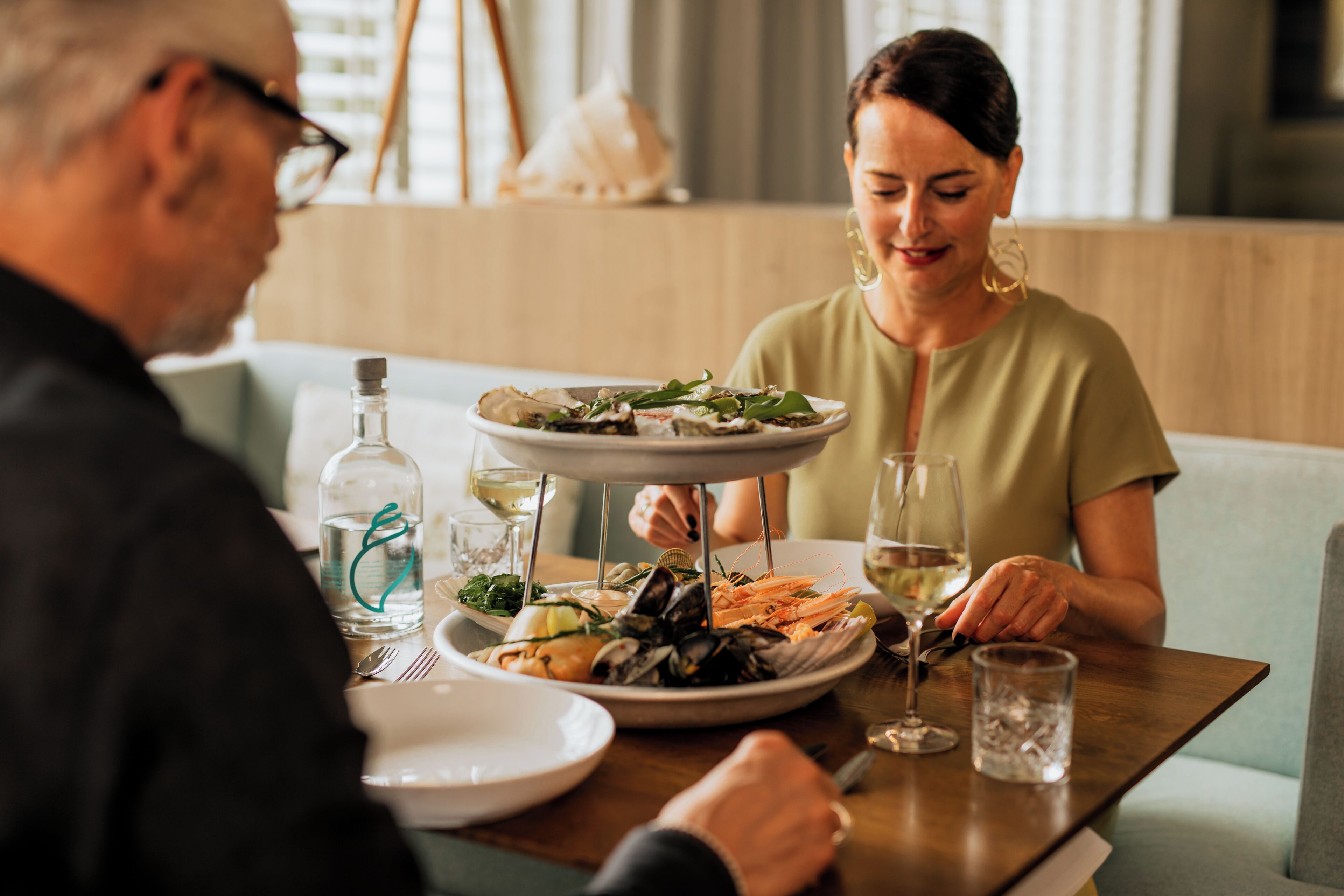 Una mesa de comedor con platos de mariscos, copas de vino y una botella de agua.