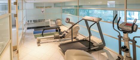 Une salle de sport équipée de tapis de course, de vélos elliptiques et de poids libres.