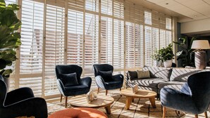 Un salon moderne doté de grandes fenêtres, de sièges confortables et d’une table basse.