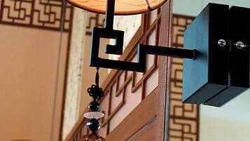 A room with a bed, a wall-mounted lamp, and a decorative hanging ornament.