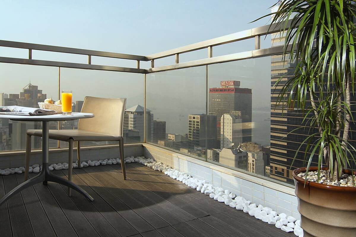 Eine Dachterrasse mit Tisch, Stuhl, einer Topfpflanze und Blick auf die Stadt.