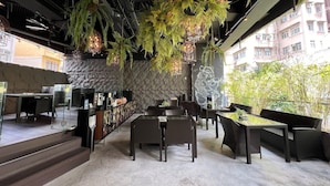 A restaurant with outdoor seating, stone walls, hanging plants, and a mural. - Lan Kwai Fong Hotel @ Kau U Fong by Dorsett Hotels (Hong Kong)
