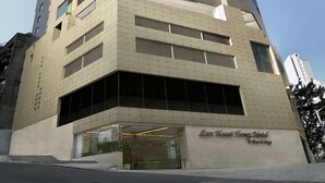 A tall, modern hotel with a prominent entrance and a clear sky in the background. - Lan Kwai Fong Hotel @ Kau U Fong by Dorsett Hotels (Hong Kong)