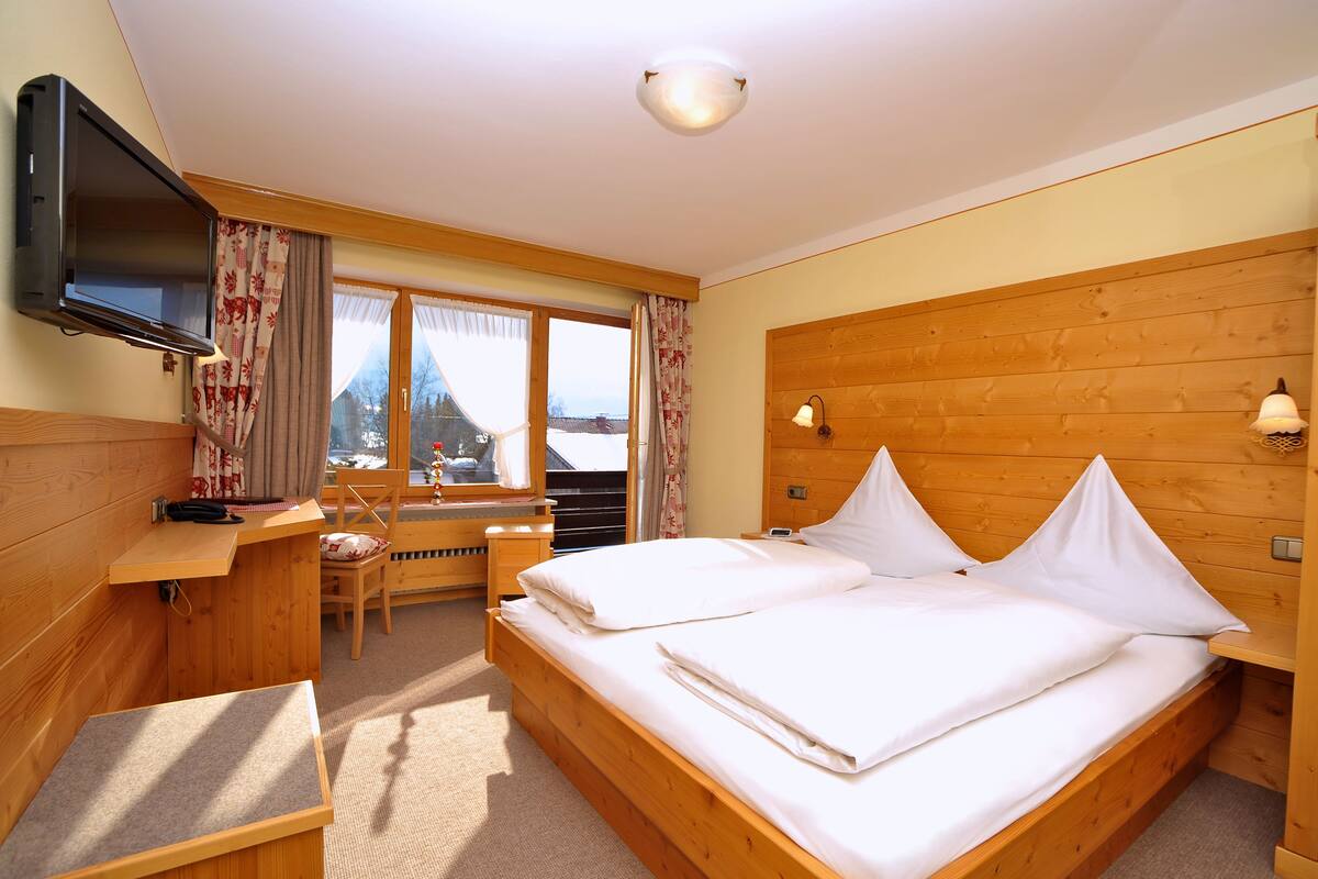Ein Zimmer mit Holzwänden, einem Bett, einem Schreibtisch und einem Fernseher.