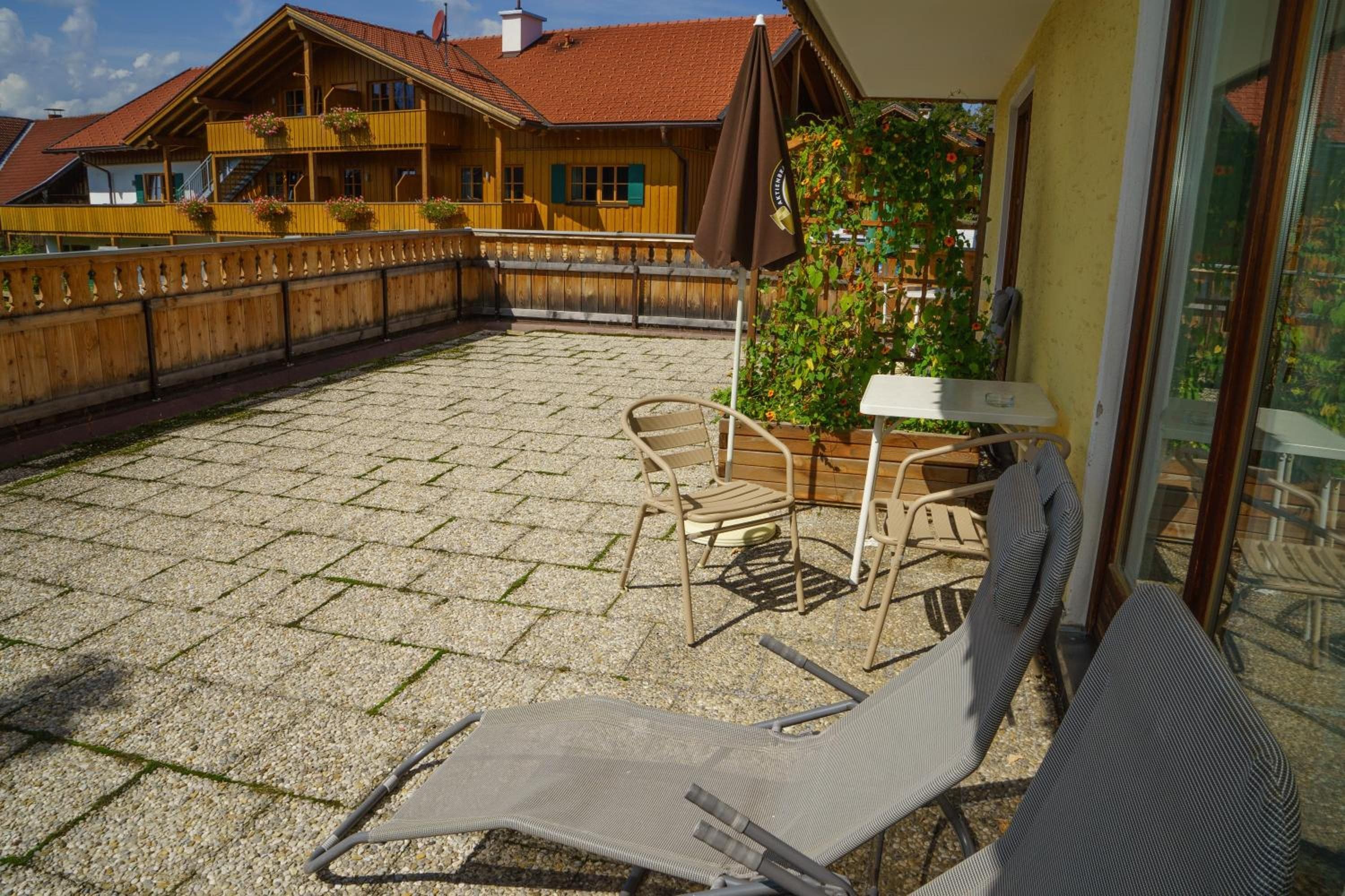 A patio area with a wooden fence, a table, and two chairs.