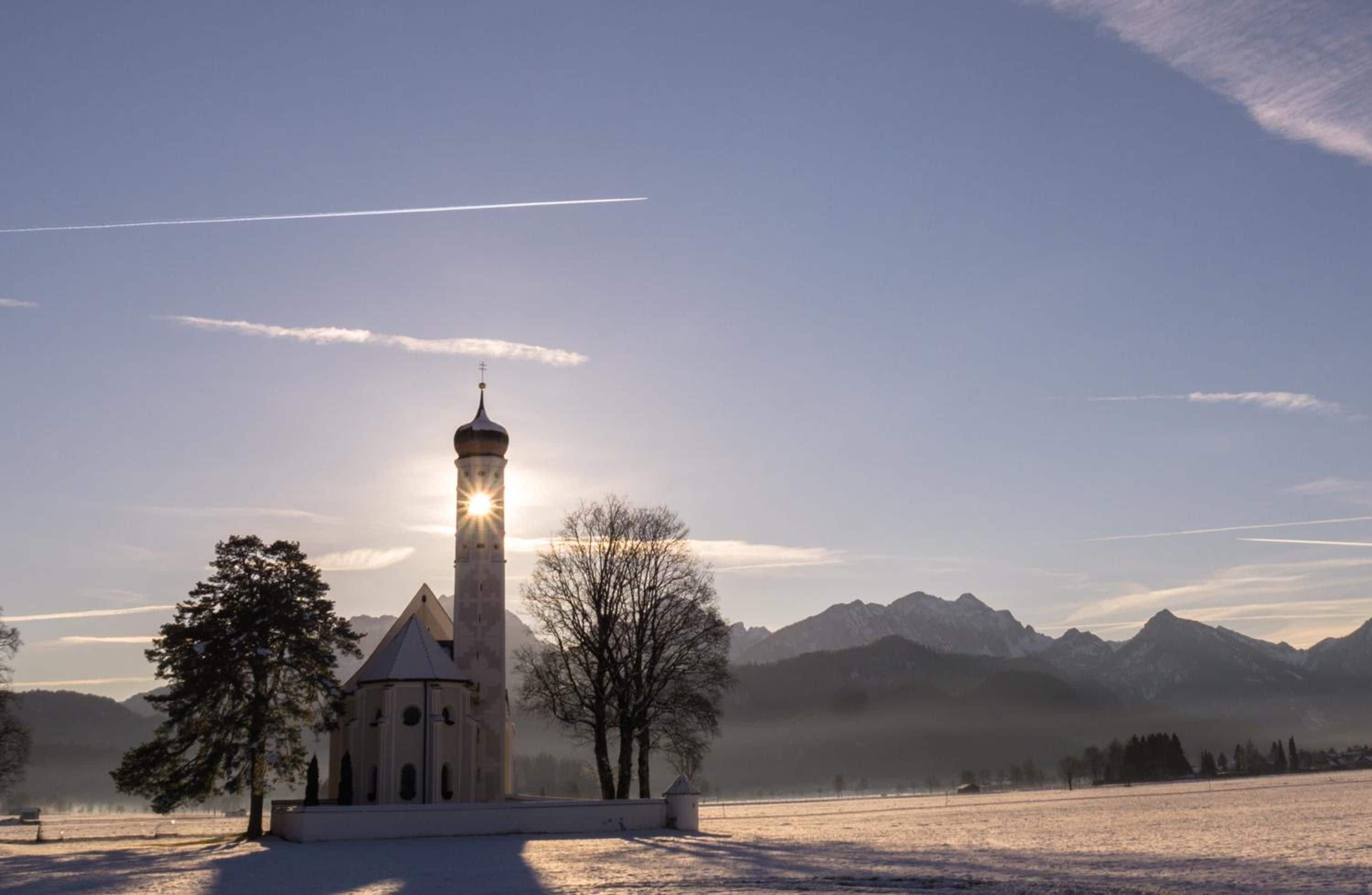 Une église dotée d’un haut clocher et surplombant un ciel dégagé.