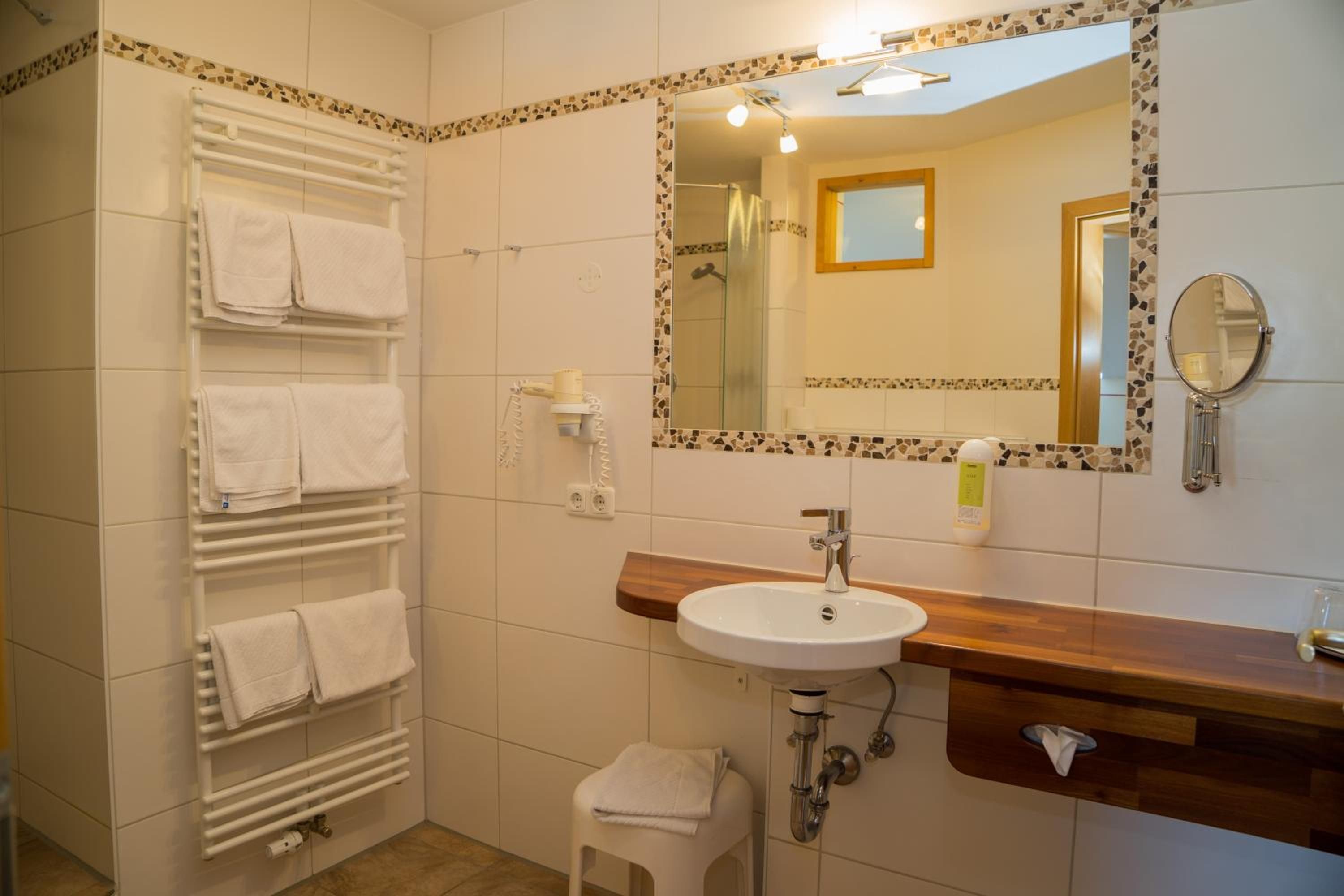 Ein Badezimmer mit einem weißen Waschbecken, einem Spiegel und einem Handtuchhalter.