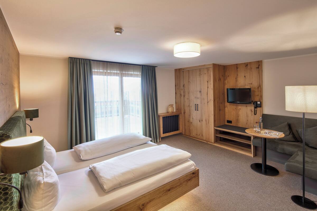 Ein Hotelzimmer mit Bett, Schreibtisch, Fernseher und einer Sitzecke.
